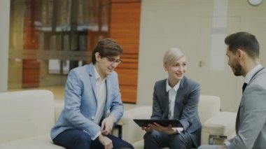 Modern ofis koltukta oturan erkek iş meslektaşları ile atış işkadını dijital tablet duscussing ile kaydırma