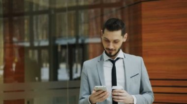 Stedicam atış smartphone ile konuşmak ve modern ofis salonunda yürüyüş neşeli işadamı