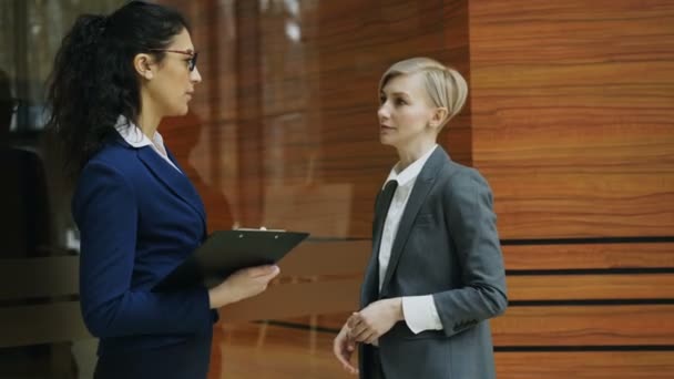 Paninning disparo de dos mujeres de negocios hablando en la oficina moderna — Vídeo de stock