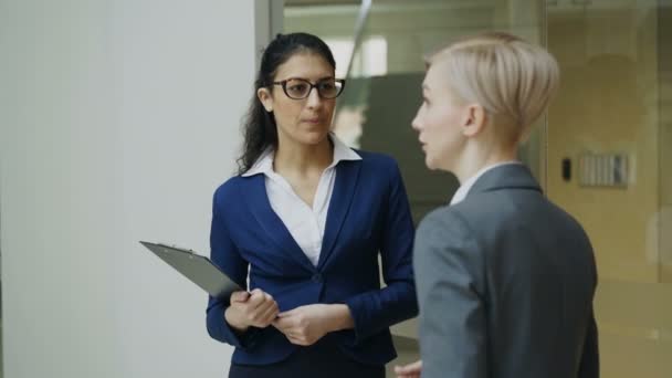 Две деловые женщины-коллеги разговаривают в современном офисе — стоковое видео