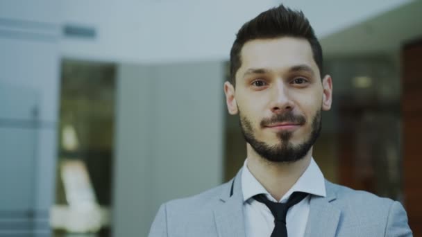 Retrato de joven empresario sonriente exitoso mirando a la cámara en la oficina moderna — Vídeo de stock