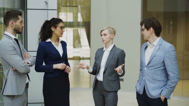 Geschäftsfrau im Gespräch mit ihren Kollegen, während sie in der Büro-Lobby steht. Gruppe von Geschäftsleuten diskutiert zukünftiges Abkommen — Stockvideo