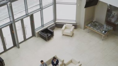 Couchs modern iş merkezi lobisinde otururken mali çizelgeleri tartışırken iş insanlar meslektaşlarının grubunun üstten görünüm aşağı eğimli