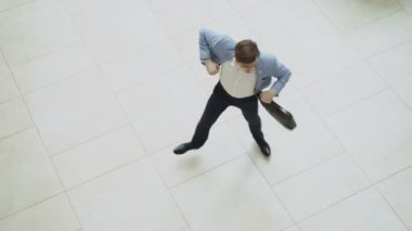 Çılgın ve komik işadamı dans ederken kimse onu izlerken ofis lobisinde evrak çantası ile Üstten Görünüm