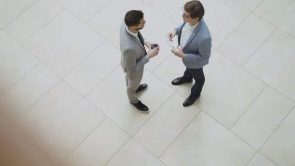 Bovenaanzicht van twee zakenlieden bespreken financieel verslag vervolgens vertellen afscheid handen schudden en weglopen in lobby van business center — Stockvideo