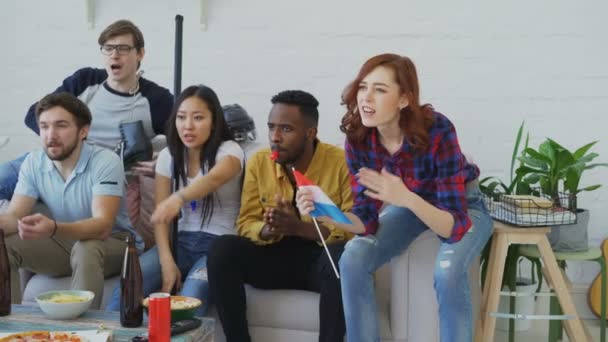 Diverso grupo de amigos fãs de esportes com bandeiras nacionais holandesas assistindo jogos de esportes de inverno na TV juntos animando a equipe favorita em casa — Vídeo de Stock