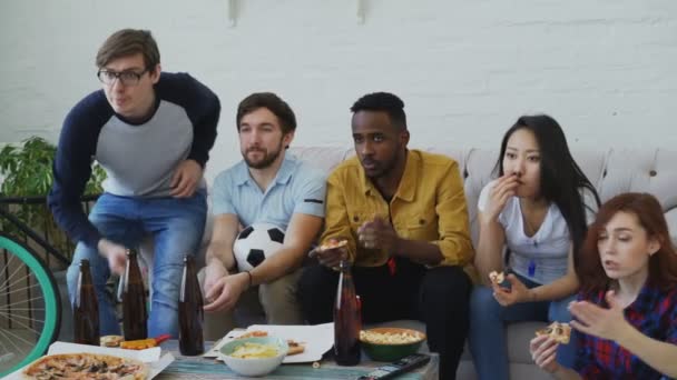 Junge Freunde schauen zu Hause gemeinsam Fußballspiel im Fernsehen und sind enttäuscht über die Niederlage ihres Lieblingsteams — Stockvideo