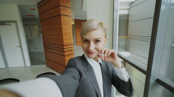 ПОВ молодої бізнес-леді в костюмі знімає селфі-фото тримає смартфон і розважається в сучасному офісі — стокове відео