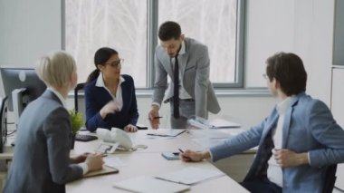 Modern ofis masada oturan kadın ve erkek meslektaşları ile raporları tartışırken işkadını