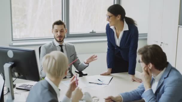 Jonge zakenman praten met mannelijke en vrouwelijke collega's zitten aan de tafel in de moderne kantoor — Stockvideo