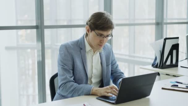 Giovane uomo d'affari che utilizza il computer portatile riceve un buon messaggio e diventa molto eccitato e felice seduto in ufficio moderno — Video Stock