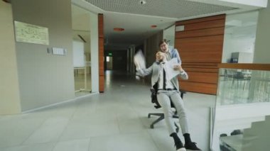 Ofis koltuğu sürme ve modern iş merkezi lobisinde eğlenirken kağıtları kusuyor iki çılgın işadamları kadeh Dooly