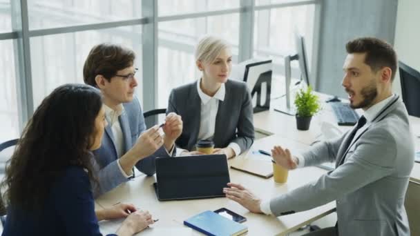 Empresario discutiendo futuro proyecto de negocio con colegas masculinos y femeninos sentados a la mesa en la oficina moderna — Vídeo de stock