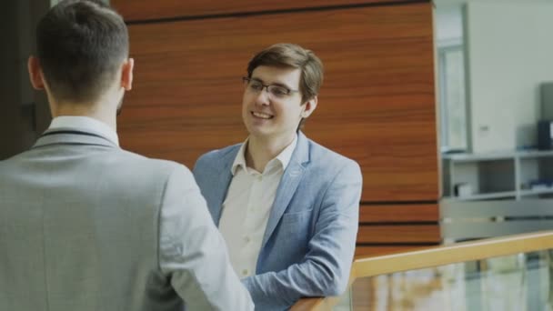 Dos colegas de negocios de pie y charlando de pie cerca de barandilla en la sala del moderno centro de negocios — Vídeos de Stock