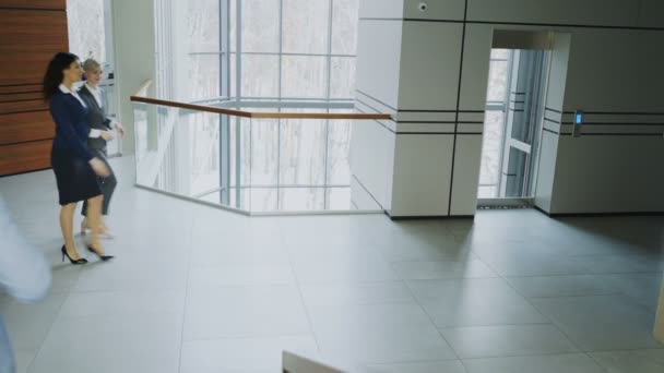 Empresarios y compañeras de trabajo caminan y se reúnen en un moderno centro de oficinas en interiores — Vídeo de stock