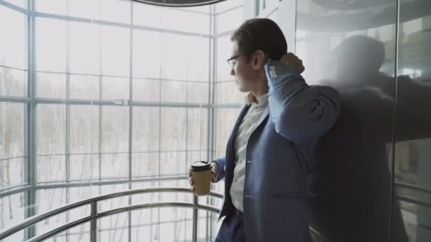 Jonge knappe zakenman in pak koffie drinken naar beneden binnen eleavator in moderne zakencentrum — Stockvideo