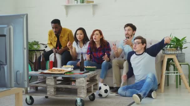 Grupo de amigos felizes assistindo jogo de esportes na TV em casa. Eles estão felizes com sua competição de vitória de equipe favorita — Vídeo de Stock