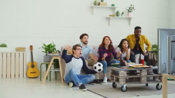 Multi grupo étnico de amigos fanáticos de los deportes viendo deporte partido en la televisión juntos saltar y animar a un nuevo gol en casa — Vídeos de Stock