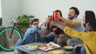 Mutlu arkadaş var parti konuşuyor ve pizza yemek. Onlar evde koltukta oturan şişe tıklatması