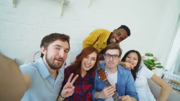 Point of view shot of multi ethnic group of cheerful friends taking selfie photos on smartphone camera while celebrating at party at home indoors — Stock Video