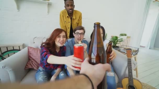 POV shot of male hand clinking beer bottle with friends while celebrating party at home indoors — Stock Video