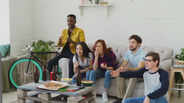 Movimento lento de jovens amigos assistindo jogo de futebol na TV juntos em casa e desapontado com sua equipe favorita perder jogo — Vídeo de Stock