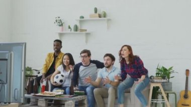 Ağır çekim çok etnik grup arkadaşıyla spor fanatikleri spor birlikte atlama ve evde yeni hedefi tezahürat televizyonda maç izlerken