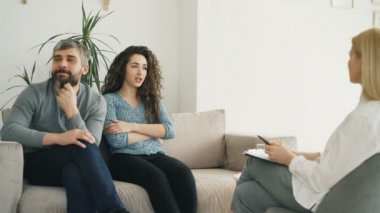 Profesyonel psikolog office ziyaret genç bir çift. Kıvırcık kadın öfkeyle savunarak ve evlilik danışmanı erkek arkadaşıyla konuşuyor