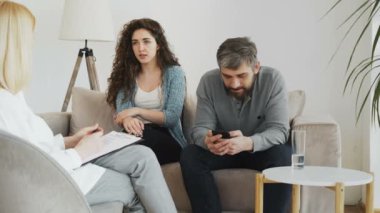 Dinleme ve yazma notlar savunarak genç kadın ve erkek arkadaşı smartphone içinde kapalı ziyaret psikoterapi office sırasında sörf yaparken kadın profesyonel psikolog