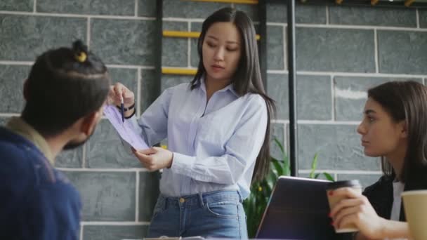 Jovem mulher asiática apresentando papel plano arquitetônico de casa para colegas de trabalho no moderno start-up escritório — Vídeo de Stock