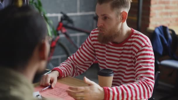 Unga hipster affärsman förklarar projektinformation till multi etniska team visar papper plan i kreativ byrå kontor — Stockvideo