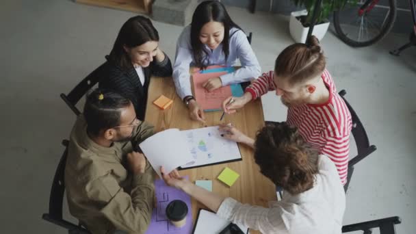 Jeune équipe de collègues d'affaires masculins et féminins qui regardent et discutent d'un nouveau projet de start-up dans un loft moderne 