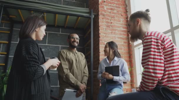 Multietniska start teamet är brainstorming och diskutera nya idéer i det moderna kontoret stående nära fönster — Stockvideo