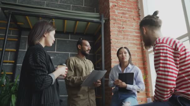 Çok etnik gruptan oluşan öğrenci takım beyin fırtınası ve pencere yanında dururken Üniversitesi'nde modern sınıf yeni fikirler tartışıyor — Stok video