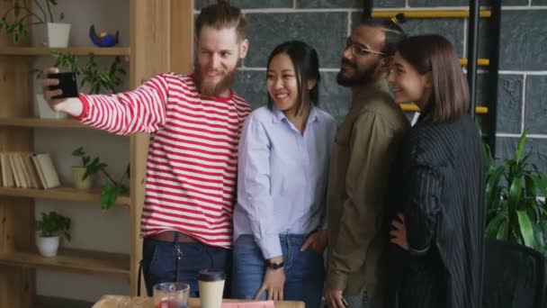 Glad multietniska team tar selfie i moderna loft office. Hipster man innehav smartphone ta självporträtt med kollegorna — Stockvideo