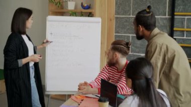 Neşeli işkadını kapalı modern loft ofiste çok etnik arkadaşlarınıza flipchart üzerinde başlangıç iş kısa açıklayan