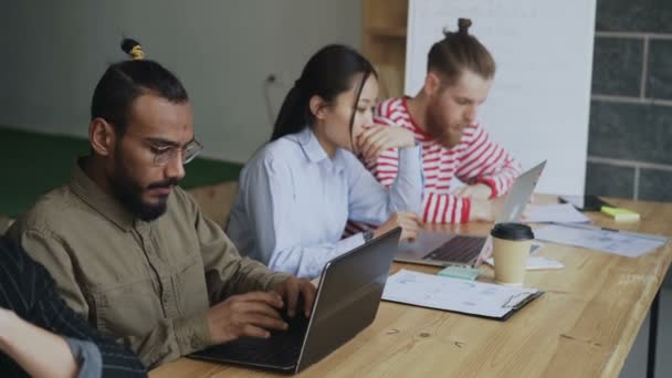 Équipe multiethnique de collaborateurs travaillant sur un projet de démarrage technologique. Africain américain concentré homme tapant sur ordinateur portable dans le bureau loft — Video
