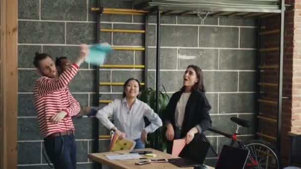 Multi-étnica start-up colegas de negocios se divierten bailando en la oficina moderna tirar documentos de papel y celebrar el éxito del proyecto — Vídeo de stock