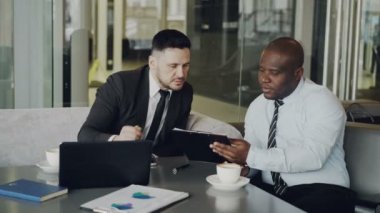 İş sözleşmeleri tartışmak ve şık kafe Not Defteri'nde bakarak iki iş arkadaşları. Afrika kökenli Amerikalı işadamı onun imza atıyor ve beyaz adamın elini sallıyor