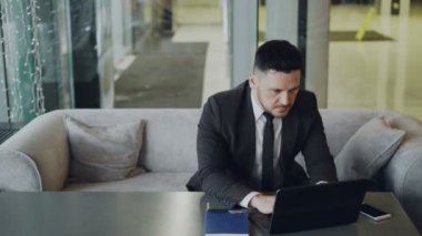 Dizüstü bilgisayarını modern kafede oturan ve çalışan siyah takım elbise içinde saygın Kafkas işadamı konsantre
