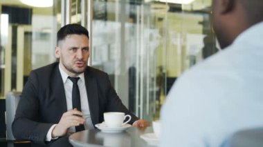 Formal giyim iş görevleri Afro-Amerikan menajeriyle modern kafede öğle yemeği molası sırasında ayarlama'emin beyaz iş adamıdır. Patron şık kalem tutar.