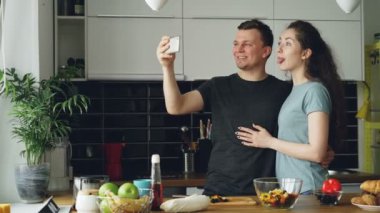 Sabahları evde mutfakta yemek yaparken smartphone kamerayla selfie fotoğraf çekmek genç komik Çift