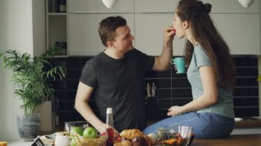Mutlu genç pişirme karınca mutfakta evde konuşmaya çift. Çekici erkek arkadaşı kesme sebze ise sabahları kahvaltı için besleme
