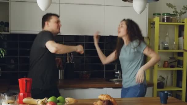 Alegre e atraente jovem casal apaixonado dançando juntos dança funky na cozinha em casa em férias — Vídeo de Stock