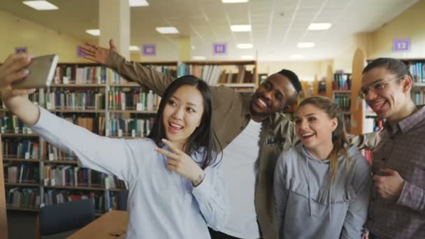 Groupe d'étudiants internationaux ont plaisir à sourire et à faire des photos selfie sur appareil photo smartphone à la bibliothèque universitaire. Des amis joyeux se reposent pendant le projet preapre ensemble 