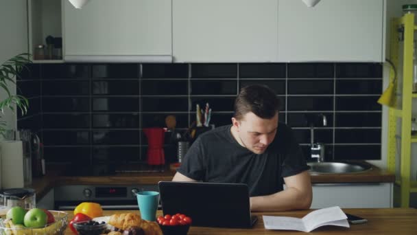 Aggódik a fiatalember fizet számlázik online használ laptop, a konyha otthon — Stock videók