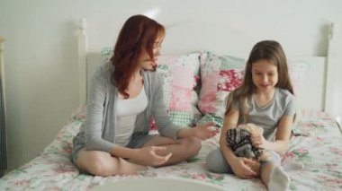 Genç dikkatli anne ve konuşmak ve yatakta evde yatak odasında otururken secrets paylaşımı küçük neşeli kızı. Relatonship ve aile kavramı
