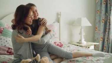 Yatakta rahat yatak evde otururken genç neşeli annesi ve teddy ile oynarken mutlu küçük kızı emabracing ayı