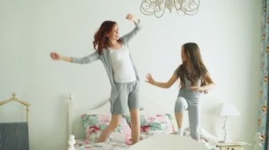 Küçük kız onun sevgi dolu bir anne ile iyi eğlenceler televizyonda gösteri dans dans modern tarzı birlikte izlerken öğrenme ve yatağa evde sabah sırasında atlama