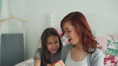 Küçük şirin kız yatakta rahat yatak evde oturan anneler günü kutlama genç mutlu annesi hediye kutusu verilmesi